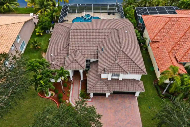 Concrete tile roof on a two story South Florida home with a brick paver driveway